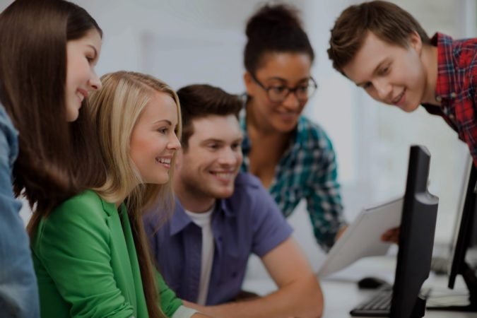 students looking at computer monitor at school
